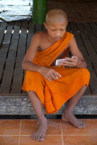 Jeune moine avec la cigarette et le mobile phone