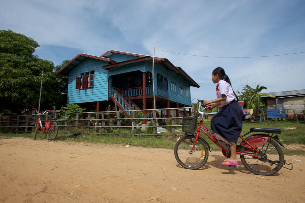 Écolière devant une maison traditionnelle à Don Khong